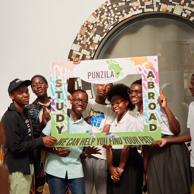Students posing with a Punzila Study Abroad photo frame at an expo