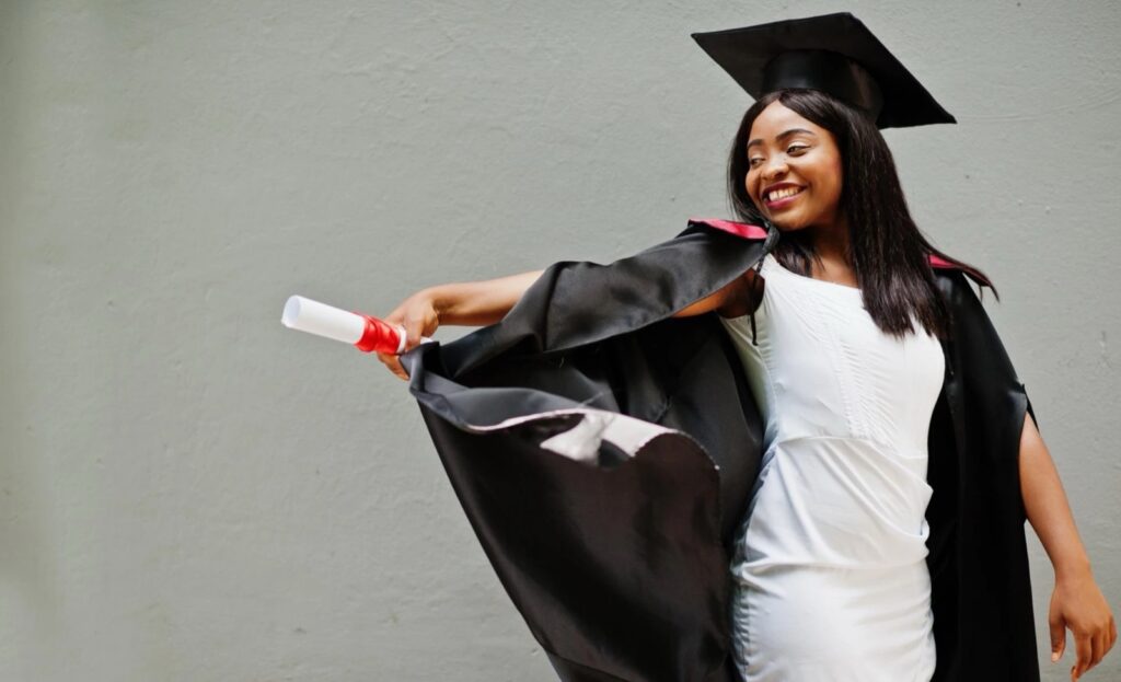 Smiling graduate in cap and gown holding her diploma